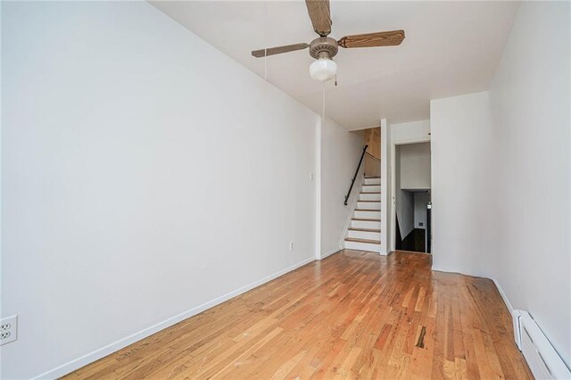 unfurnished living room with ceiling fan, baseboard heating, and light hardwood / wood-style flooring