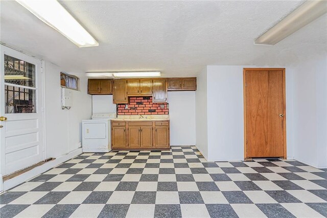 kitchen featuring washer / clothes dryer, sink, and a textured ceiling