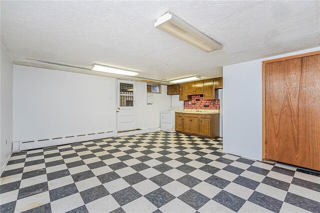 interior space with washer / clothes dryer, a baseboard heating unit, sink, and a textured ceiling