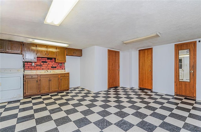 kitchen featuring washer / clothes dryer, sink, and a textured ceiling