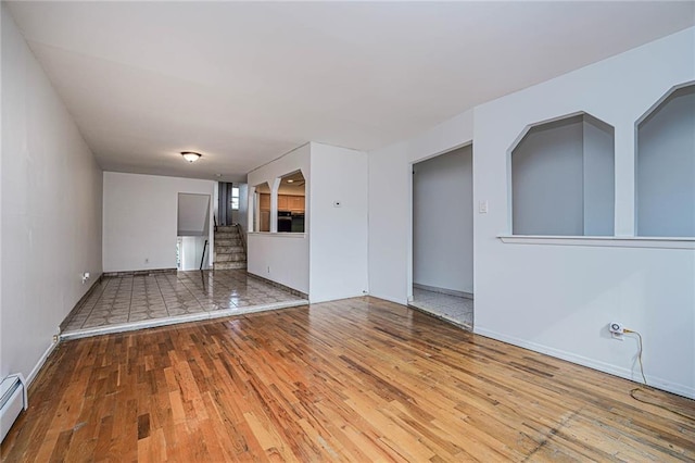 unfurnished living room featuring a baseboard heating unit and wood-type flooring