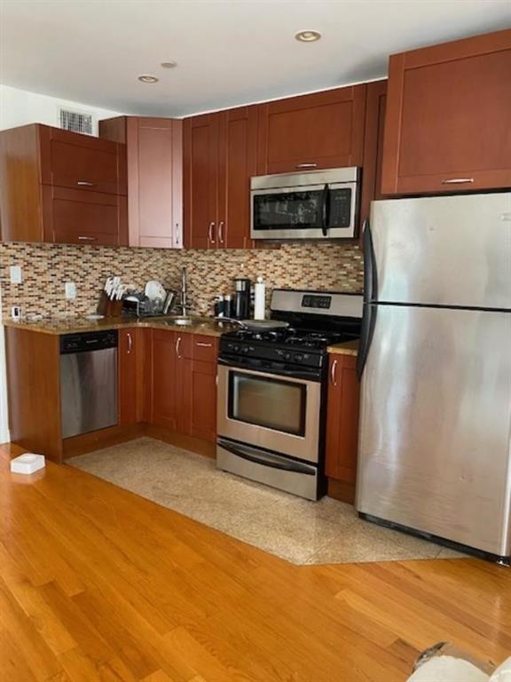 kitchen featuring sink, appliances with stainless steel finishes, light hardwood / wood-style flooring, and tasteful backsplash