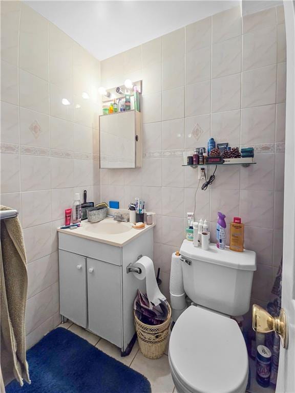 bathroom featuring tasteful backsplash, toilet, tile walls, vanity, and tile patterned flooring