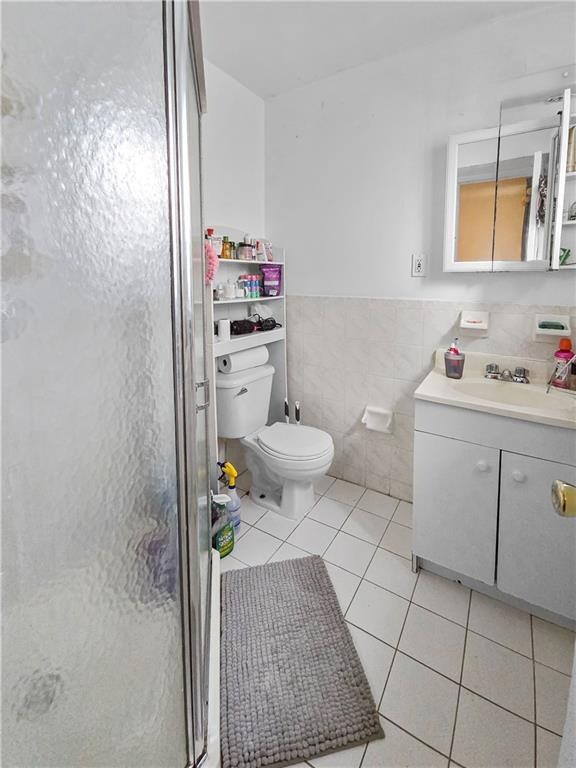 bathroom featuring vanity, tile walls, toilet, and tile patterned floors