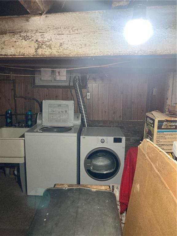 washroom featuring washing machine and dryer, sink, and wooden walls