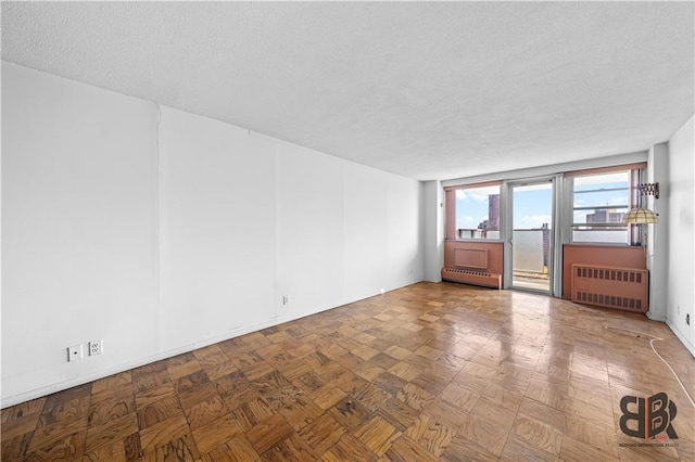 empty room featuring a baseboard radiator, a textured ceiling, radiator heating unit, and parquet floors