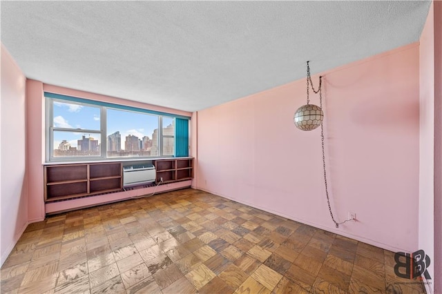 unfurnished room featuring a textured ceiling, baseboard heating, and a wall mounted AC