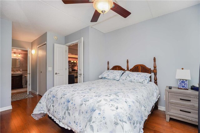 bedroom with ceiling fan, dark wood-type flooring, sink, and ensuite bath