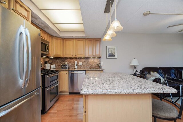 kitchen with a breakfast bar, backsplash, a center island, and stainless steel appliances