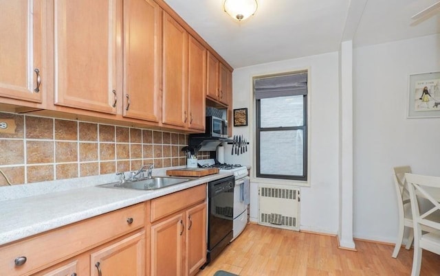 kitchen with radiator, sink, tasteful backsplash, light hardwood / wood-style floors, and white gas range oven