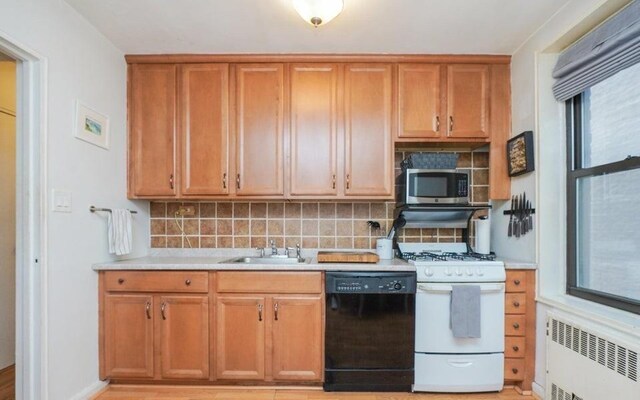 kitchen with tasteful backsplash, black dishwasher, radiator, and gas range gas stove