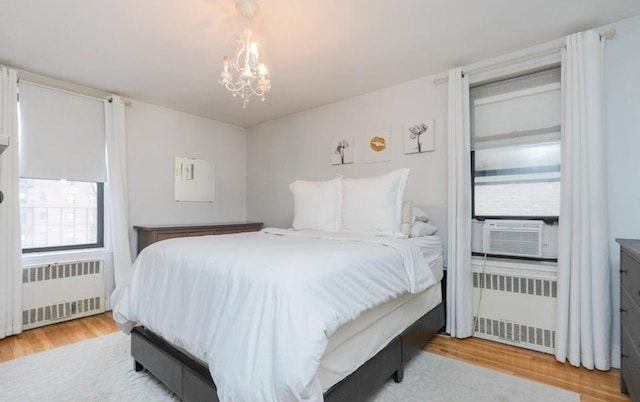 bedroom featuring radiator heating unit, light hardwood / wood-style floors, and an inviting chandelier