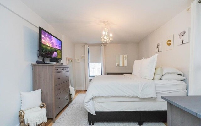 bedroom with light hardwood / wood-style flooring and a chandelier