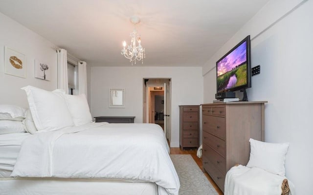 bedroom featuring an inviting chandelier and light wood-type flooring