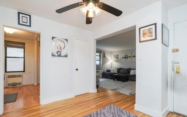 corridor featuring radiator heating unit, hardwood / wood-style flooring, and plenty of natural light