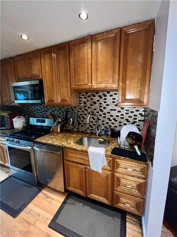 kitchen featuring backsplash, light hardwood / wood-style floors, sink, and appliances with stainless steel finishes