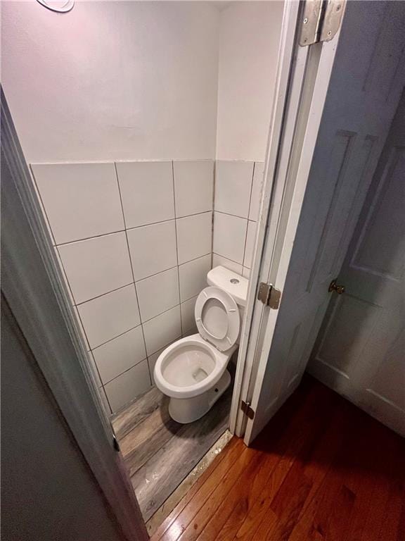 bathroom with wood-type flooring, toilet, and tile walls