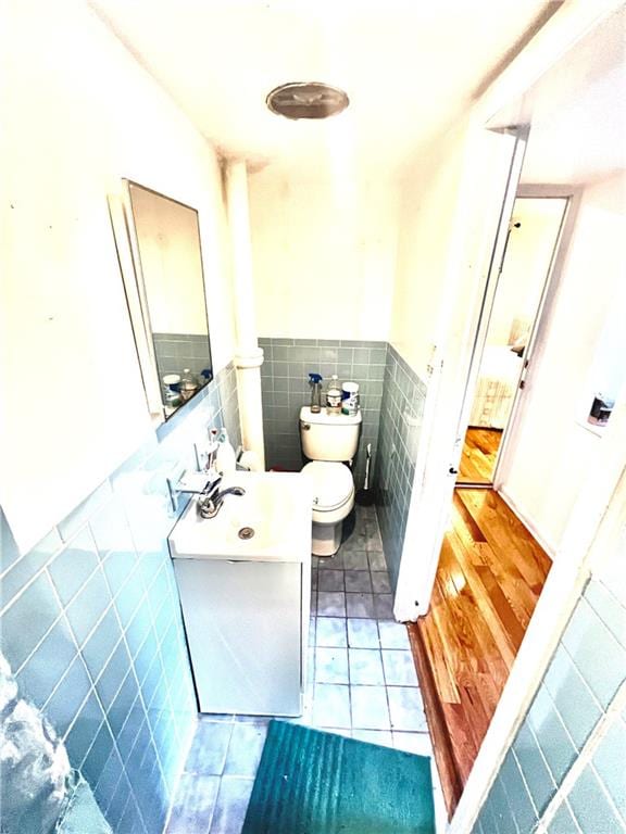 bathroom featuring tile patterned flooring, vanity, toilet, and tile walls