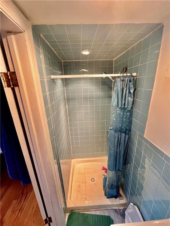 bathroom featuring curtained shower, wood-type flooring, and tile walls