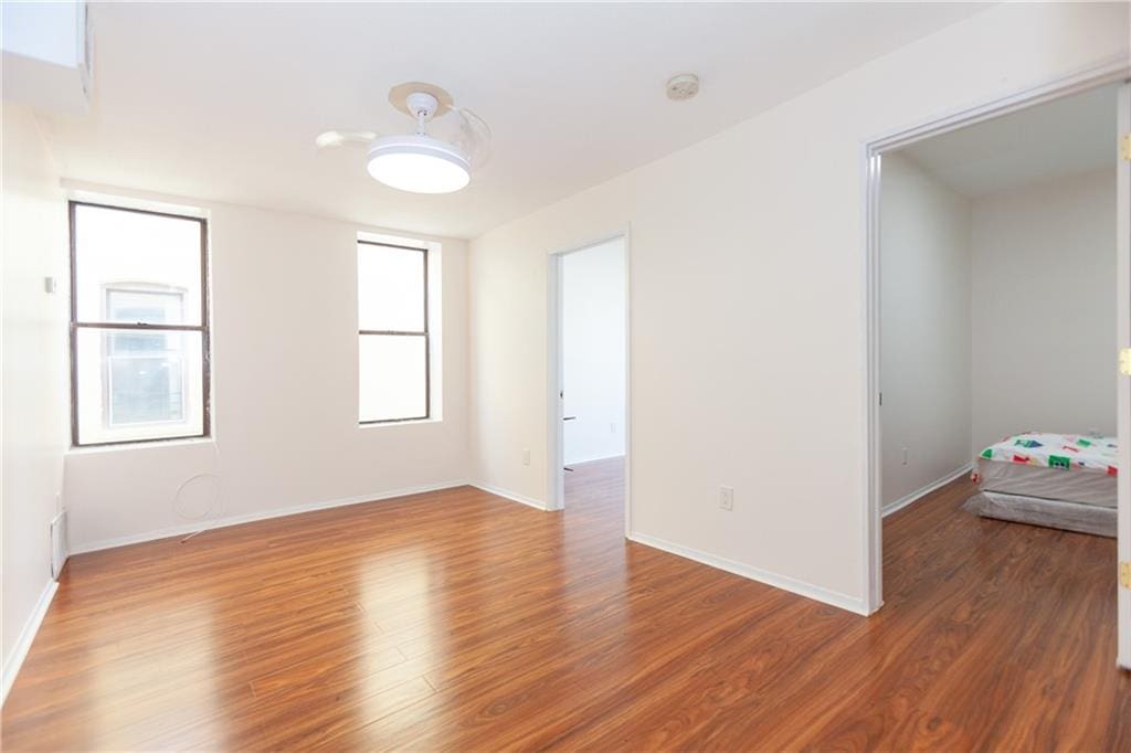 unfurnished room with baseboards and wood finished floors