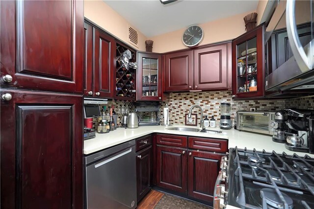 kitchen with appliances with stainless steel finishes, dark hardwood / wood-style floors, sink, and backsplash