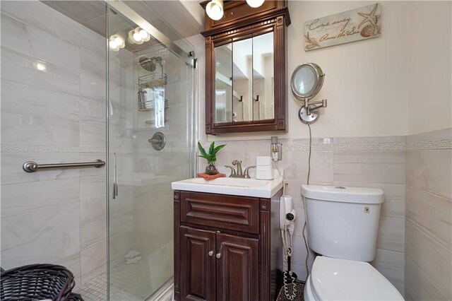 bathroom with vanity, toilet, an enclosed shower, and tile walls