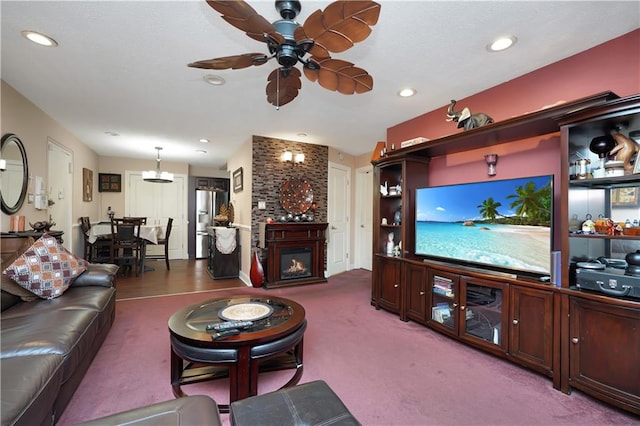 carpeted living room with a large fireplace and ceiling fan