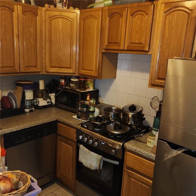 kitchen with stainless steel appliances, light tile patterned floors, and backsplash