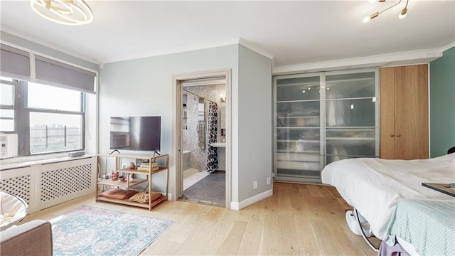 bedroom featuring a closet, crown molding, ensuite bath, and light hardwood / wood-style flooring