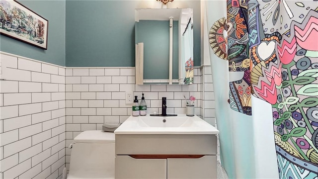 bathroom featuring vanity, tile walls, and toilet