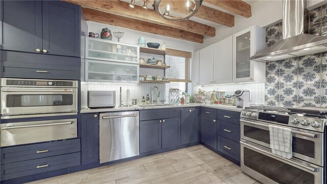 kitchen featuring tasteful backsplash, wall chimney exhaust hood, stainless steel appliances, and blue cabinets