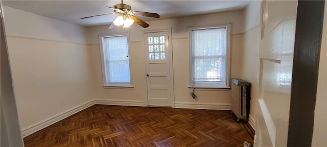 doorway with radiator, ceiling fan, and dark parquet floors