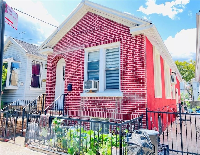 view of front of home featuring cooling unit, brick siding, and fence