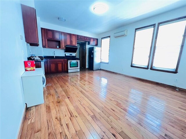 kitchen featuring a wall mounted air conditioner, light hardwood / wood-style flooring, and appliances with stainless steel finishes