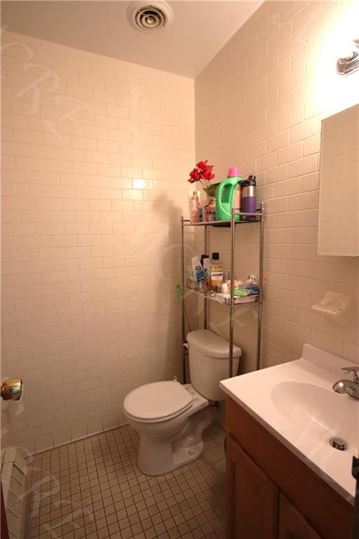 bathroom with vanity, tile patterned floors, toilet, and tile walls