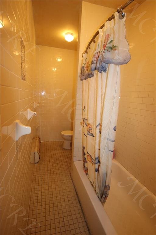 bathroom with shower / bath combo, tile walls, tile patterned floors, and toilet