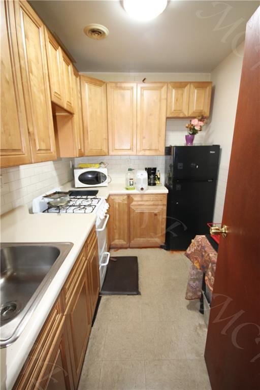 kitchen featuring stainless steel range, sink, tasteful backsplash, and light tile patterned floors