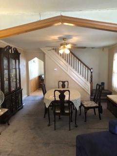 dining area featuring beam ceiling, ornamental molding, carpet flooring, and ceiling fan