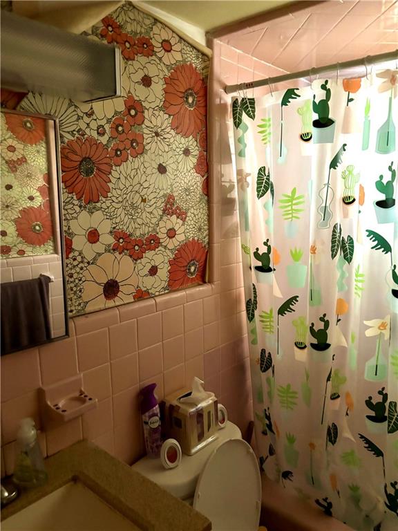 bathroom with toilet and tile walls