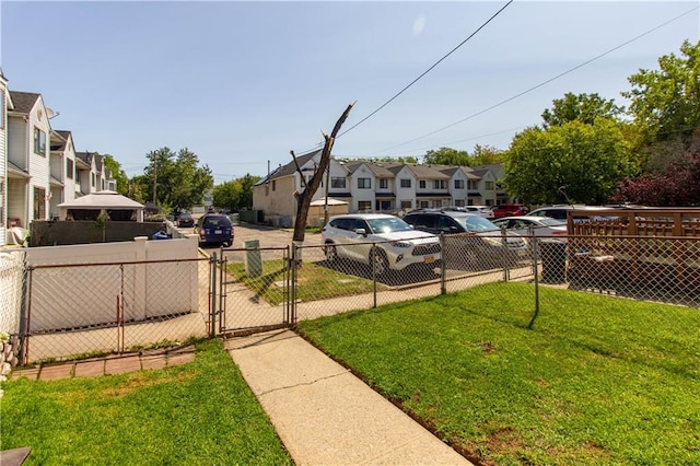 view of yard featuring a residential view, fence, and a gate