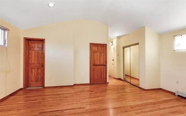 spare room with vaulted ceiling and light hardwood / wood-style flooring