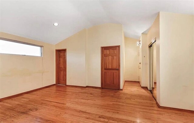 spare room featuring vaulted ceiling and light hardwood / wood-style floors