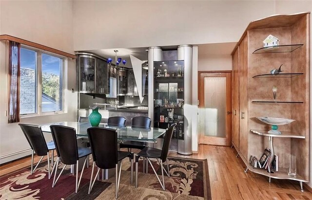 dining area featuring a towering ceiling, light hardwood / wood-style floors, and baseboard heating