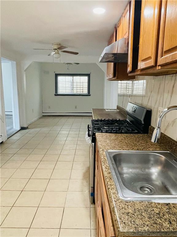 kitchen with sink, light tile patterned floors, stainless steel gas range, ventilation hood, and baseboard heating