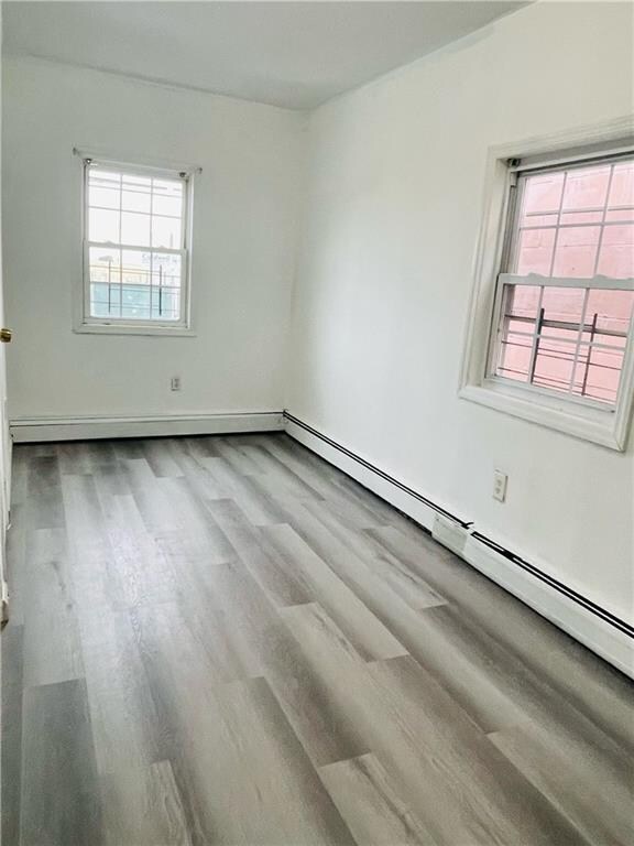 empty room featuring light wood-type flooring and a baseboard radiator