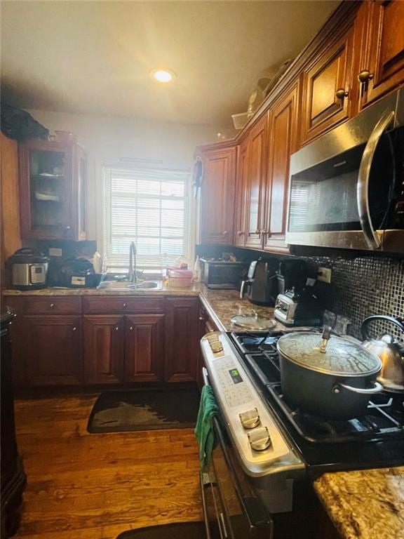 kitchen with stove, dark wood-type flooring, sink, and stone countertops