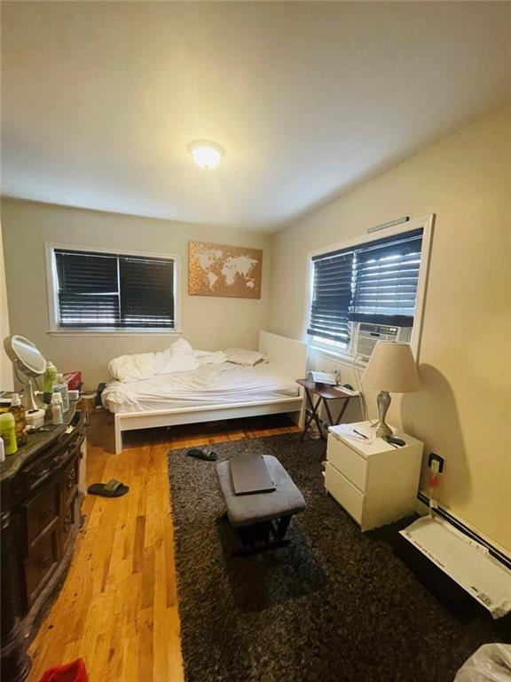 bedroom featuring a baseboard heating unit and light hardwood / wood-style floors