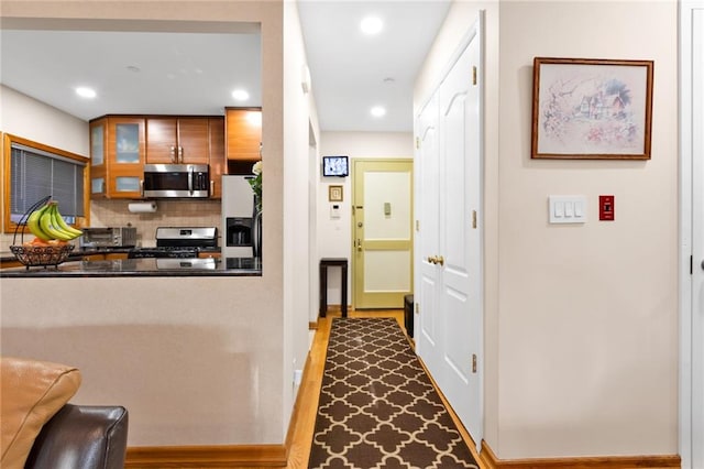 kitchen with stainless steel appliances, dark countertops, recessed lighting, backsplash, and glass insert cabinets