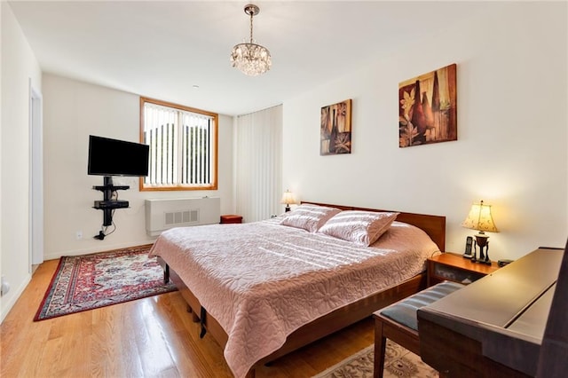 bedroom with wood finished floors and an inviting chandelier