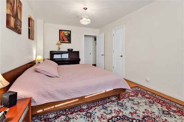 bedroom with baseboards, wood finished floors, and an inviting chandelier